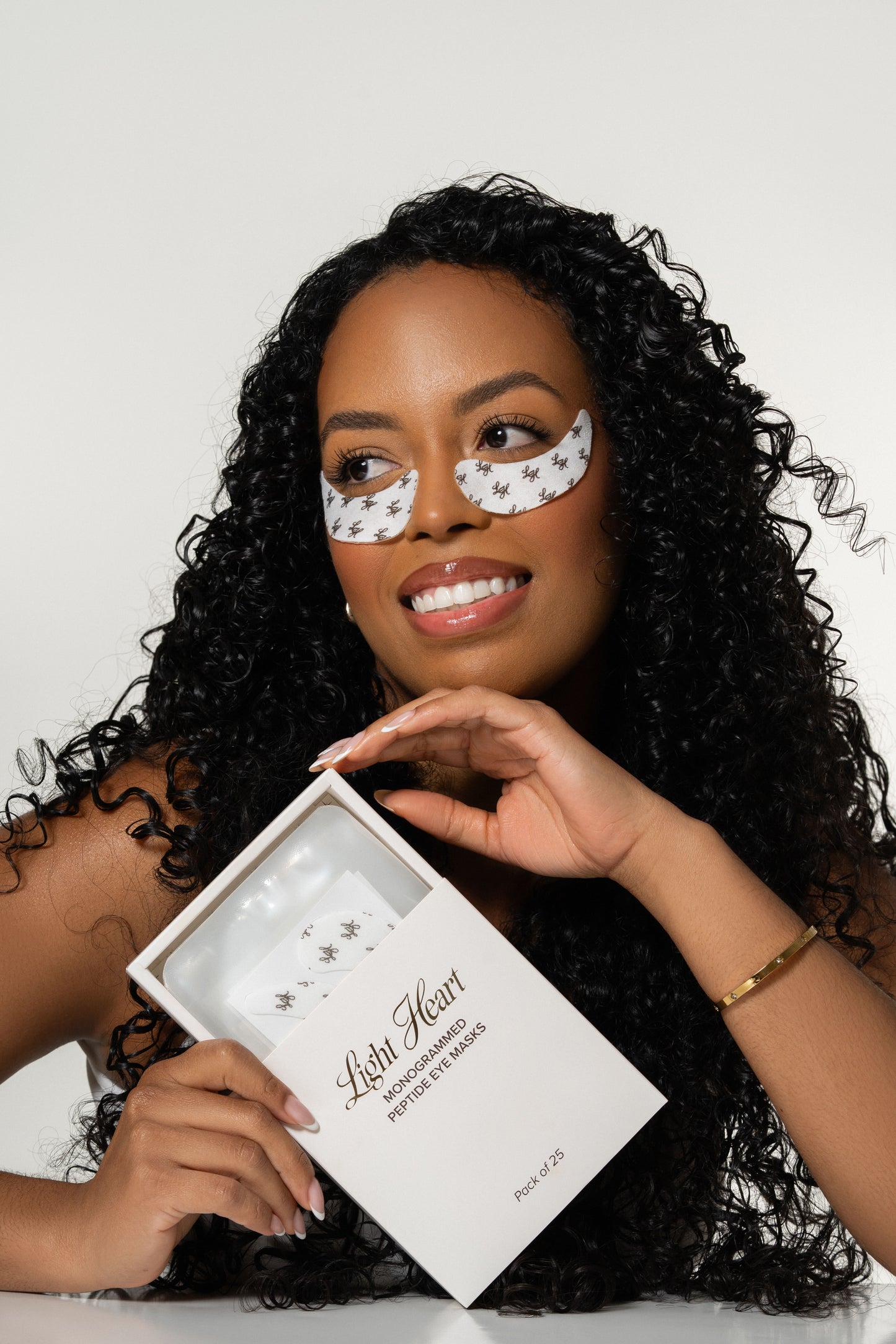 Woman showcasing Light Heart monogrammed peptide eye masks used during professional eyelash extension services.